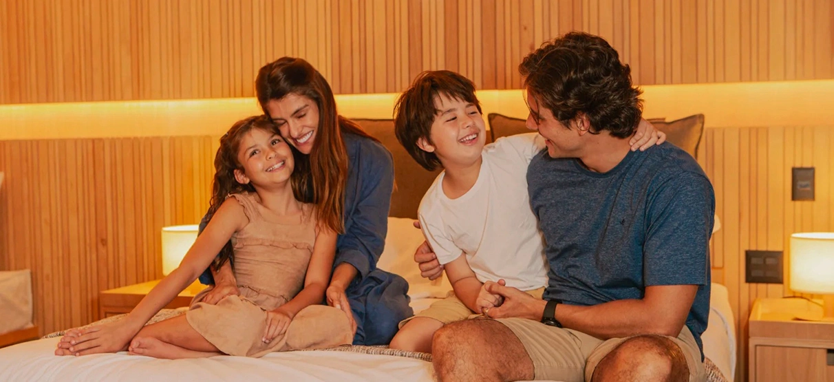 familia sentada na cama conversando e sorrindo