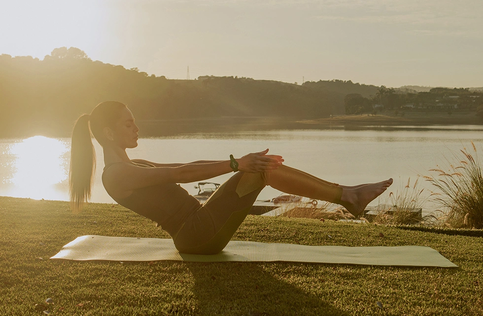 mulher praticando yoga a beira da represa do clara ibiuna